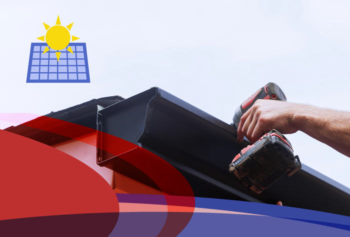 Worker using a cordless drill to secure a black aluminum gutter during a professional gutter installation service on a rooftop